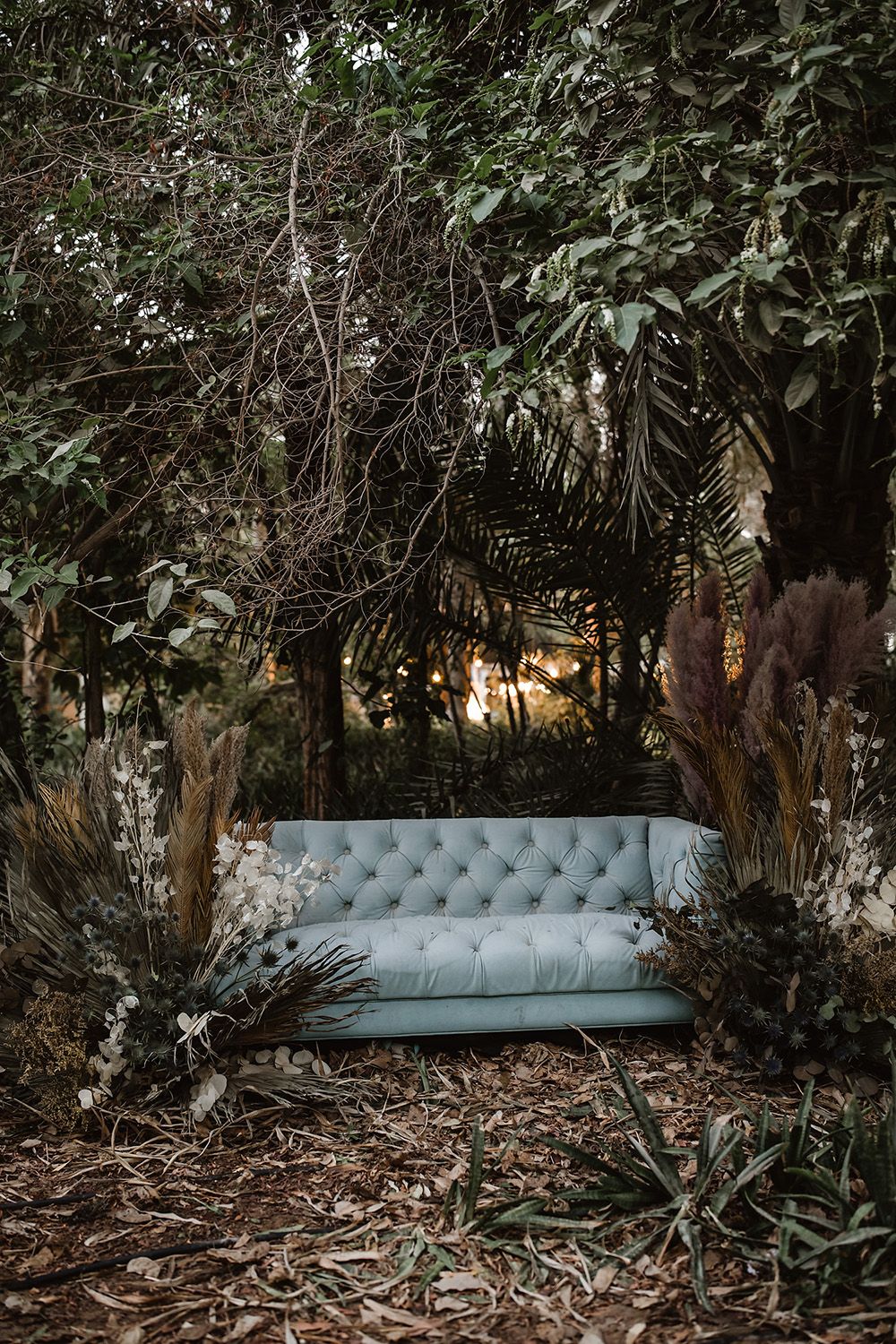 Elegant blue tufted chaise lounge set in a lush garden setting.