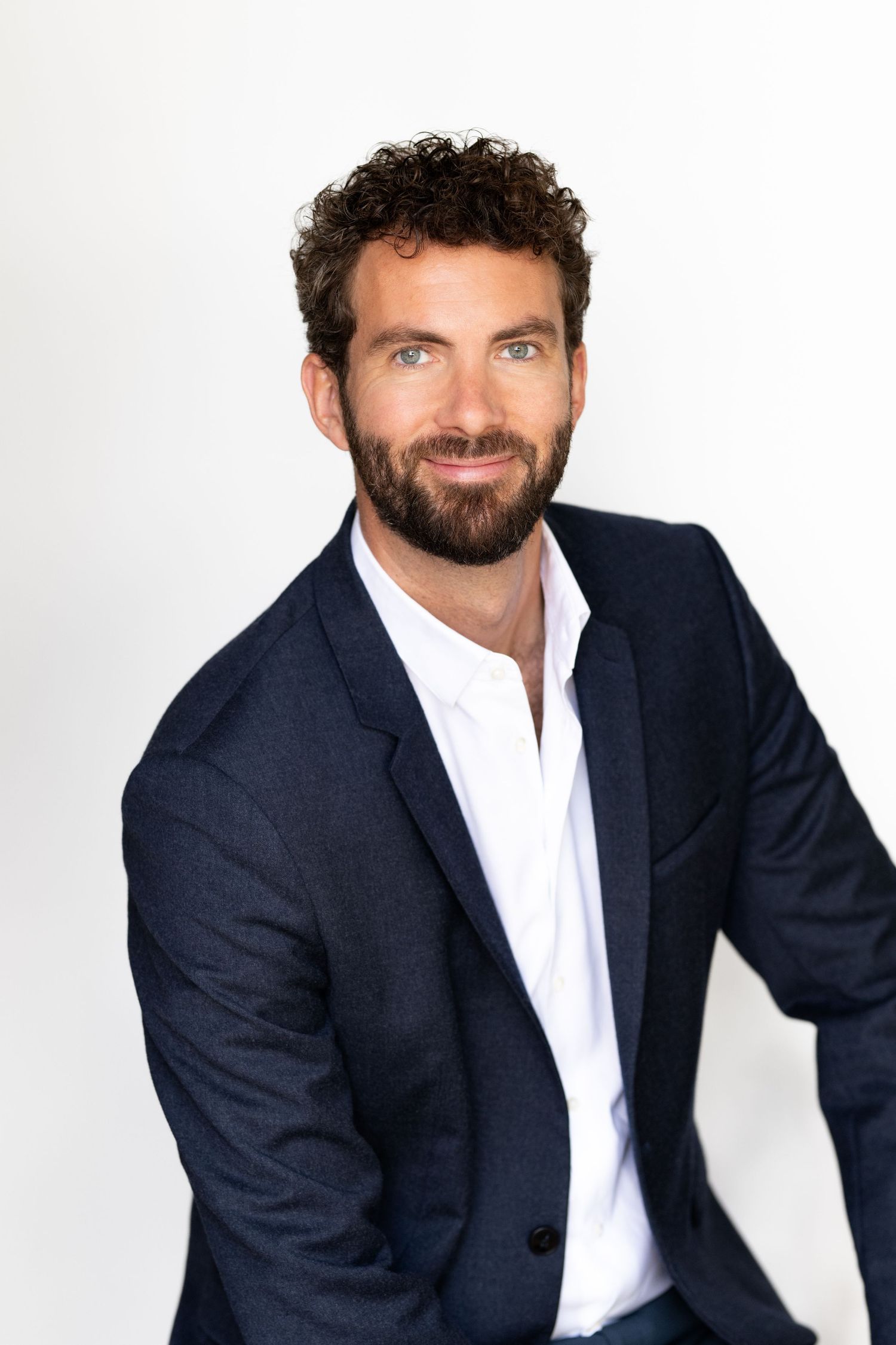 Professional headshot series of a person in a navy suit against white background.