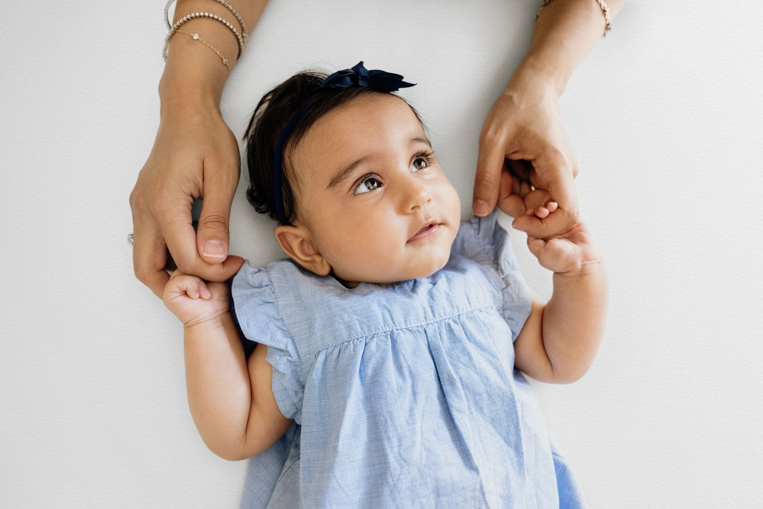Baby in light blue dress during lifestyle photo session with natural lighting.