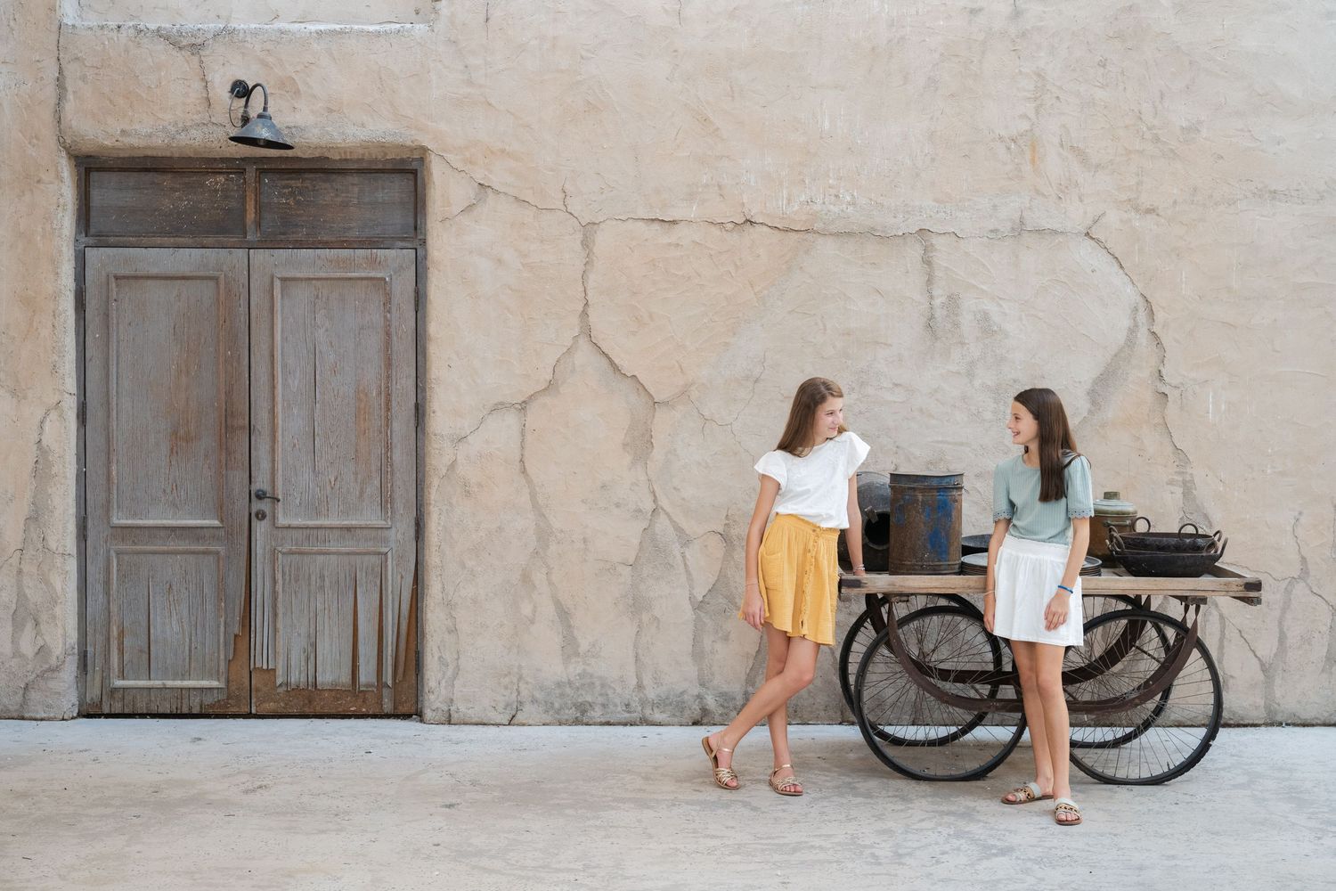 A bicycle is visible in the background of a stone-walled courtyard setting.