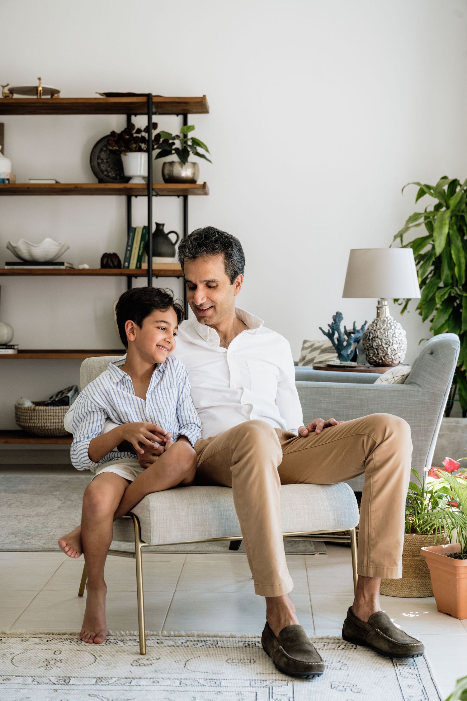 Parent and child sharing intimate moment in modern living room with wooden shelves.