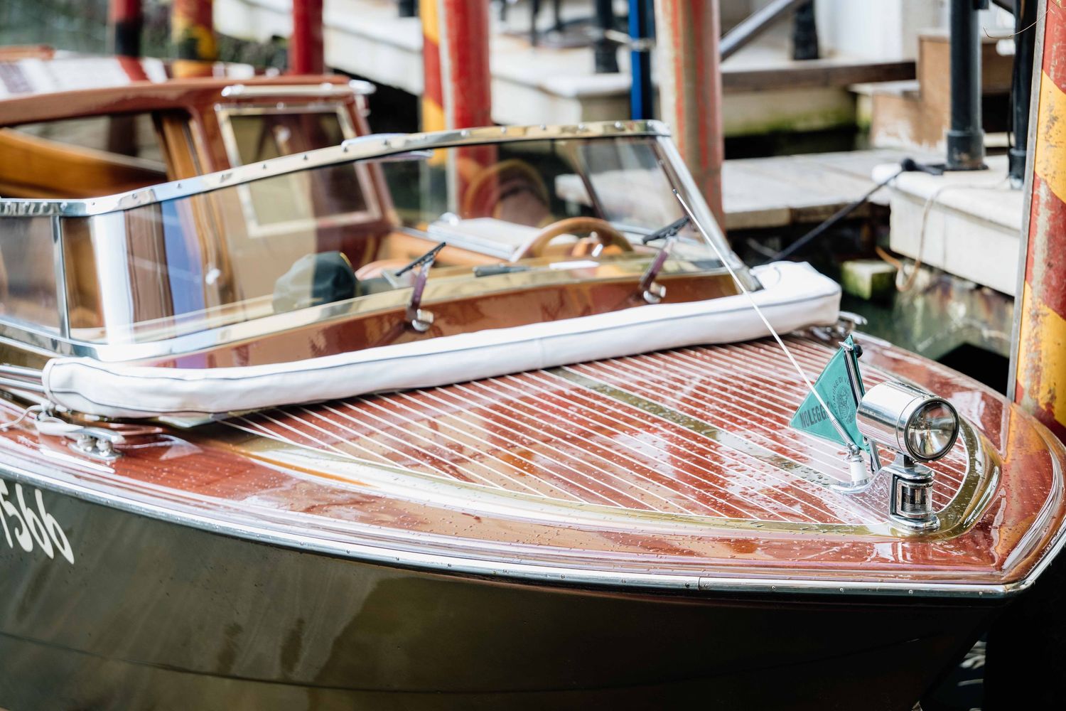 Row of traditional Venetian gondolas moored along a narrow canal with historic buildings.