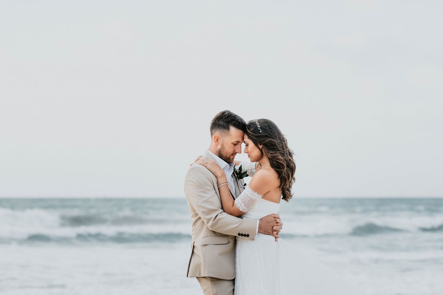 Romantic beach wedding portrait with waves crashing in background.