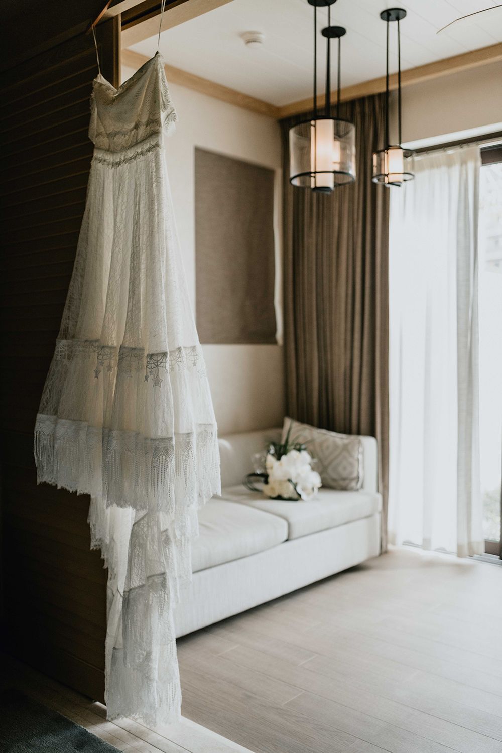 Modern hotel room interior with hanging pendant lights and sheer curtains.