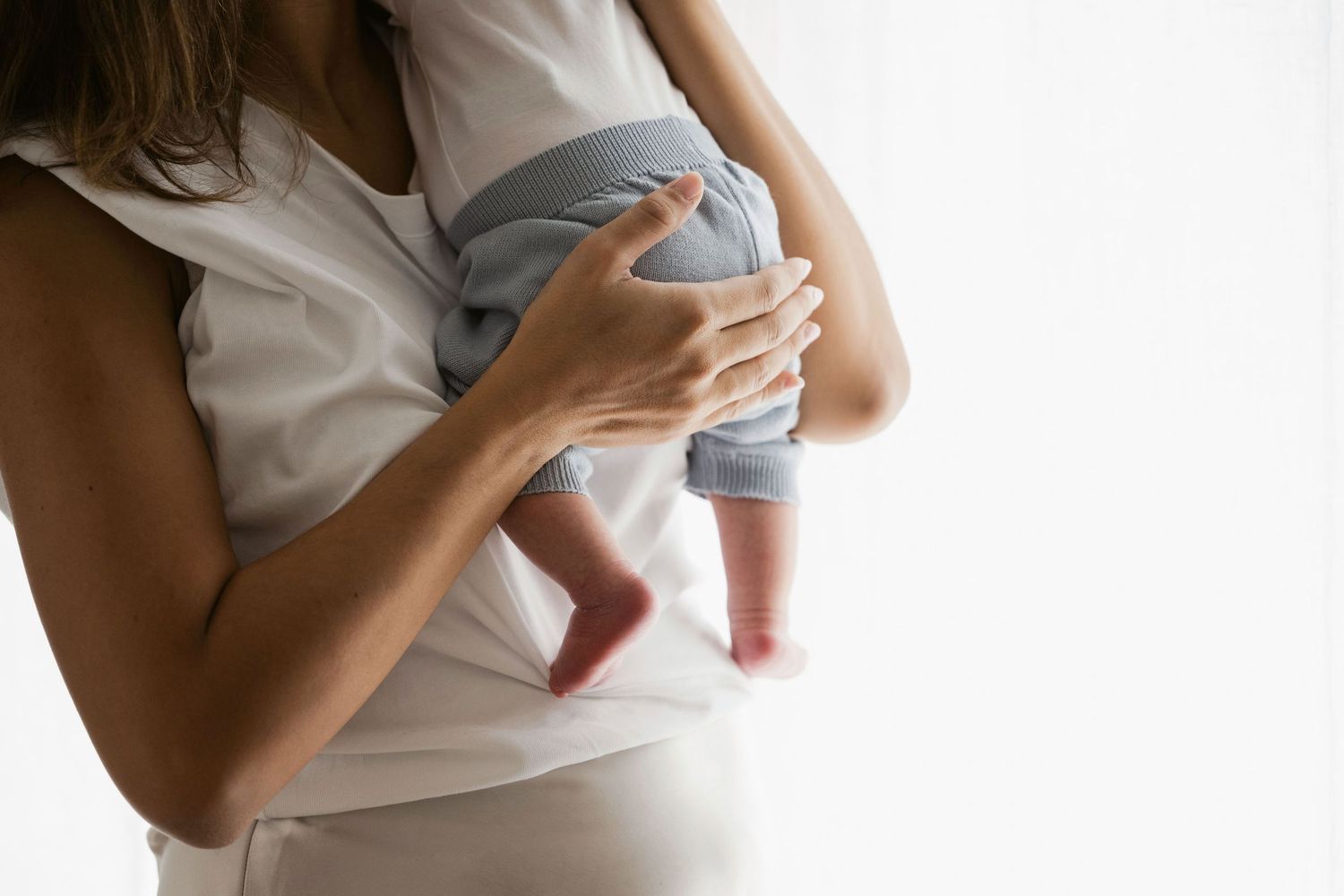 Newborn detail shot of mother holding him, gently patting him