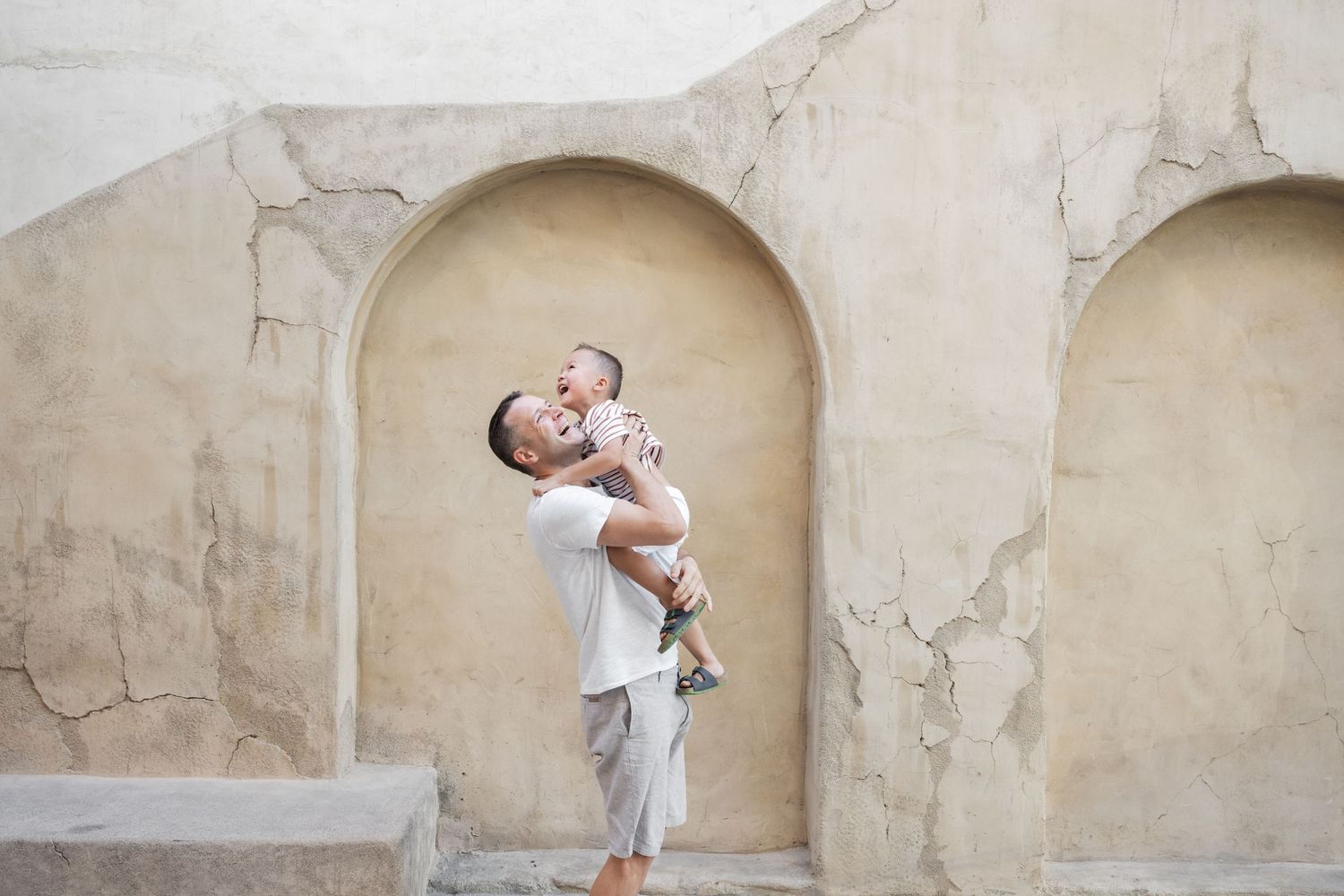 Family portrait session against a textured beige wall with arched alcoves.