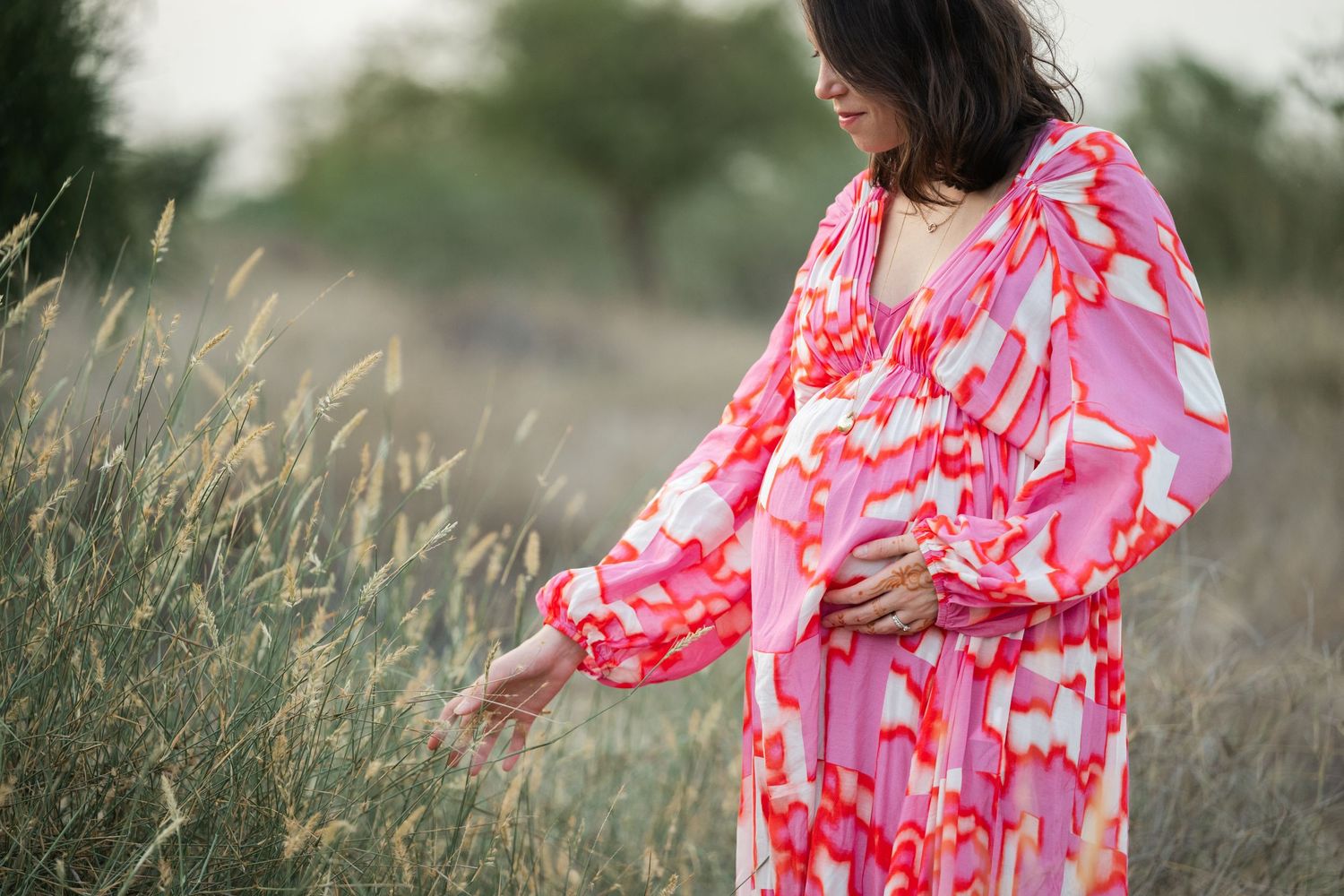 Pink floral dress flows elegantly against desert brush and natural scenery.
