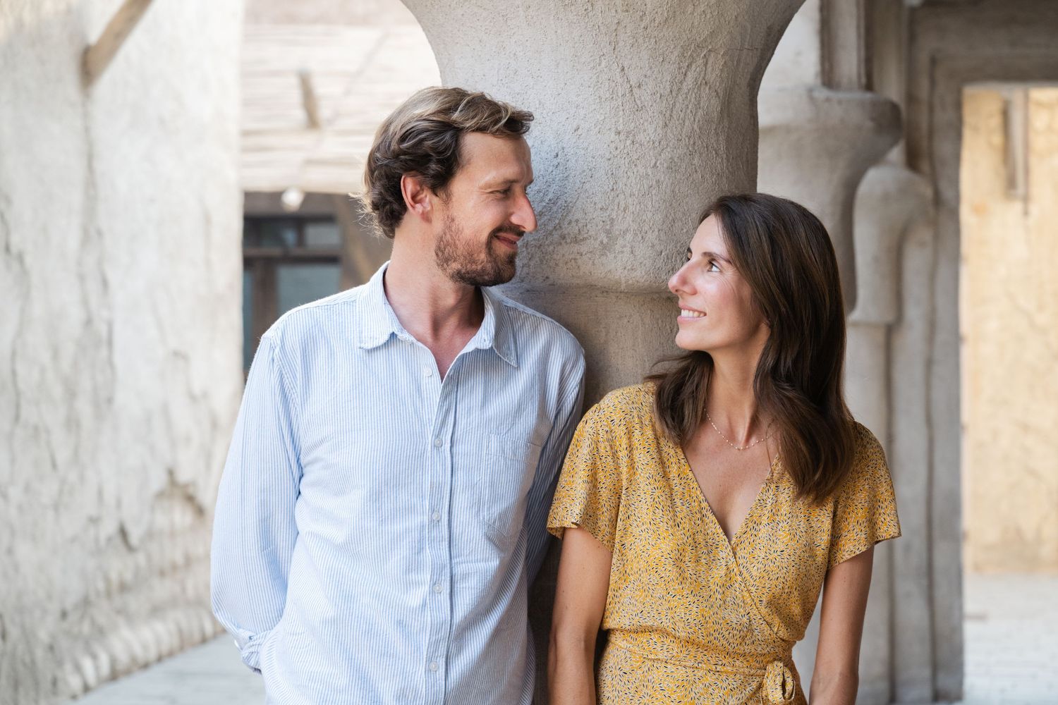 A couple poses together in an elegant stone colonnade setting.