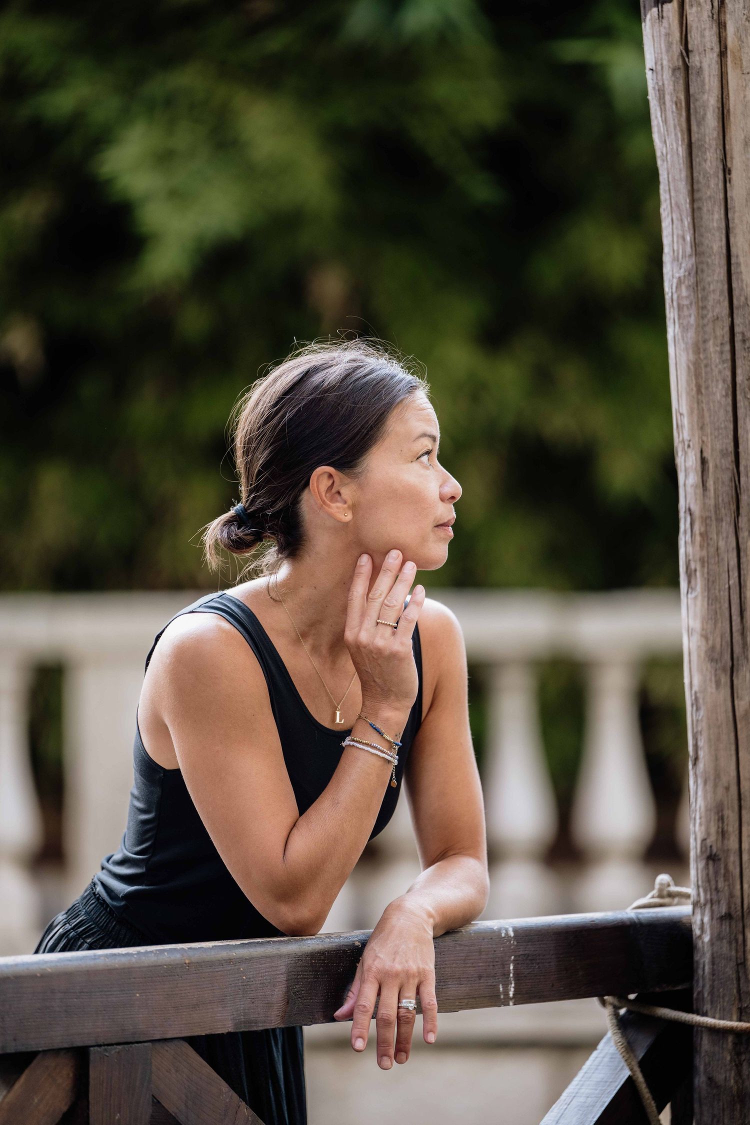 Person in black leaning on wooden railing overlooking scenic Venice canal.