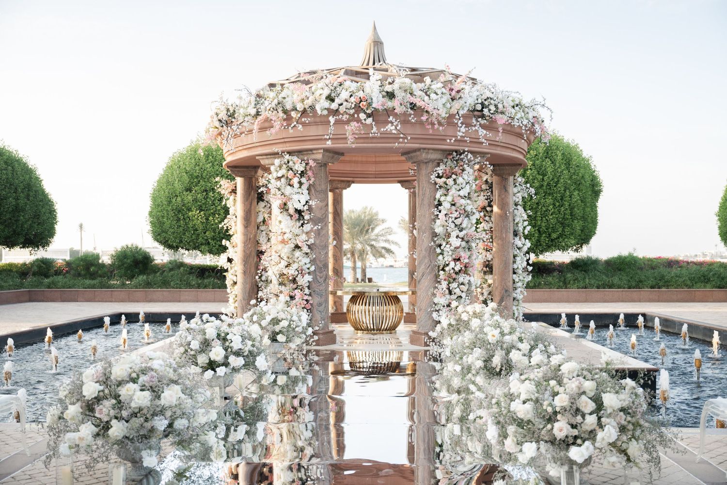Elegant wedding gazebo decorated with white floral arrangements and surrounded by manicured gardens.