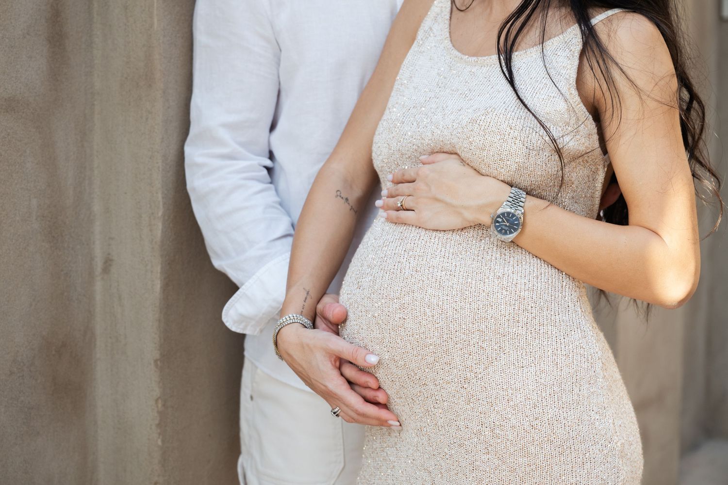 Couple's maternity photoshoot in formal attire against architectural backdrop.
