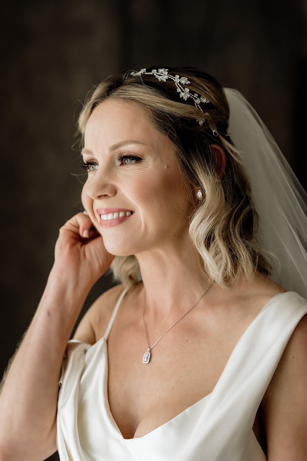 Bride with delicate headpiece and veil shows joyful expressions in portrait series.