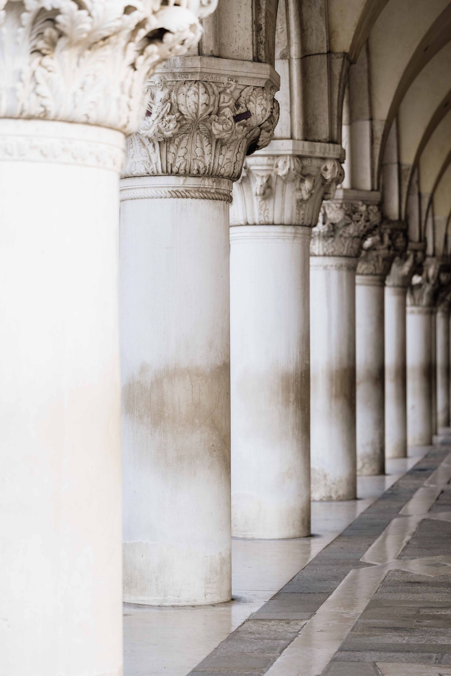 Row of ornate classical columns with carved Corinthian capitals in Venice's Doge's Palace.