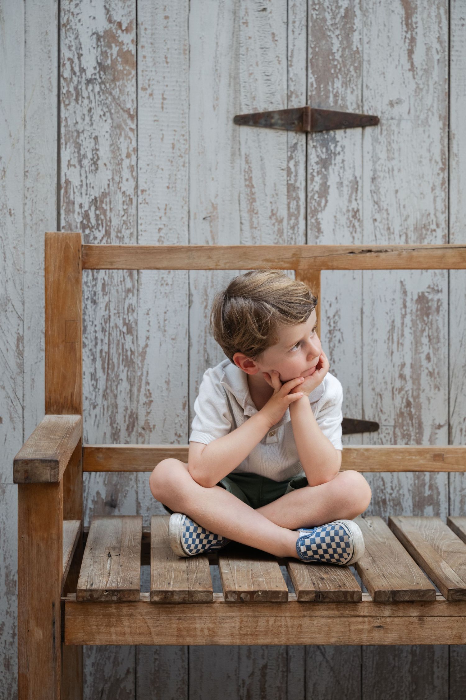 Child lying on wooden bench with distressed rustic background showing signs of sadness or distress.