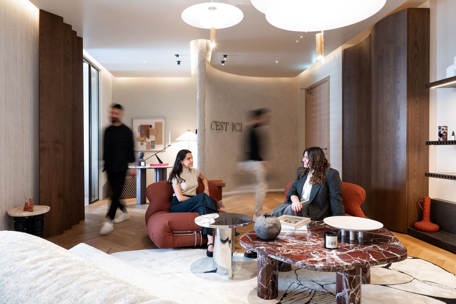 Modern office interior with white pendant lights and comfortable seating areas.