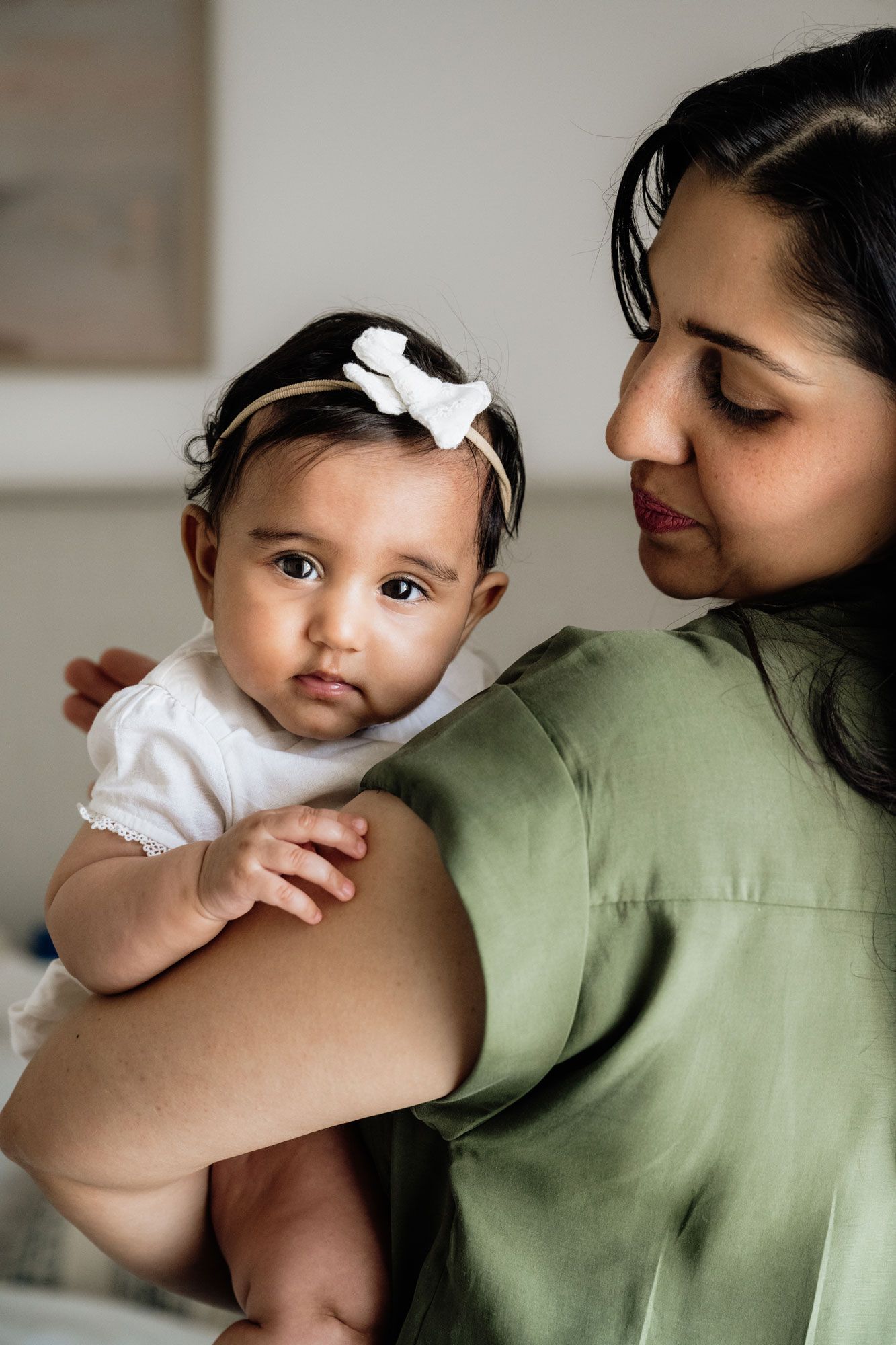 A series of tender moments between a baby in white and her mother in green, shown in a sequence of connected photos.