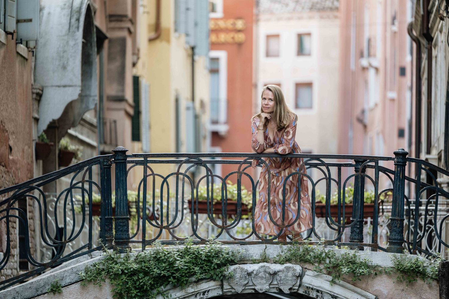 Vintage turquoise door with ornate stone archway in Venice creates atmospheric backdrop for fashion photoshoot.