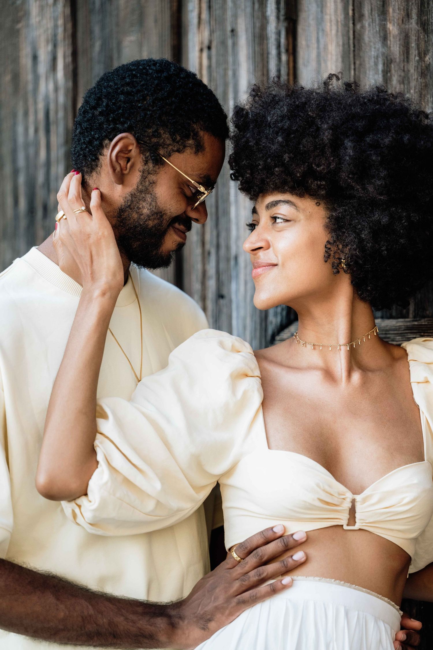 Elegant couple's photoshoot featuring romantic poses against rustic backdrop.