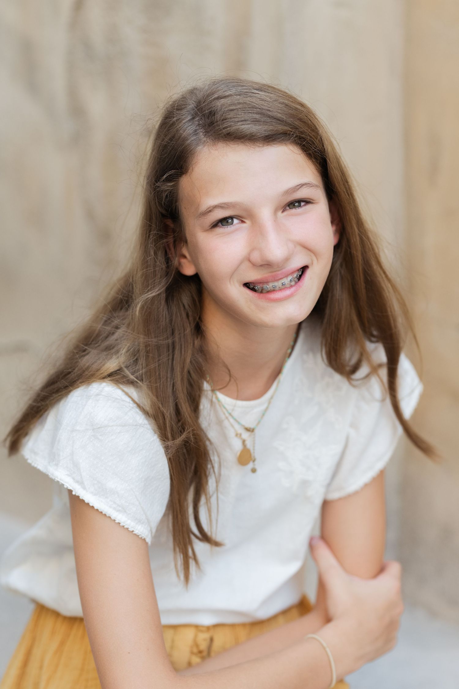Young person in white lace top smiling and posing playfully.