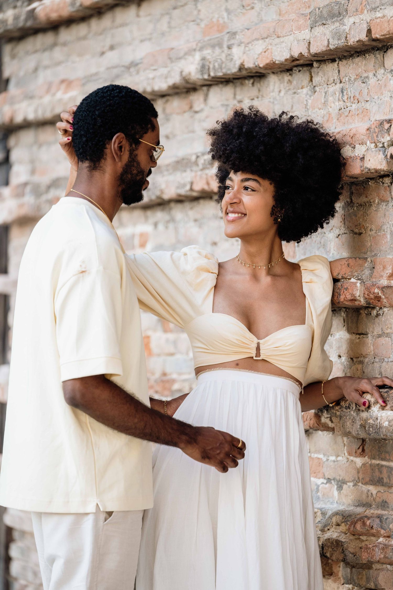 An intimate couple's photoshoot showing tender moments against a textured brick background.