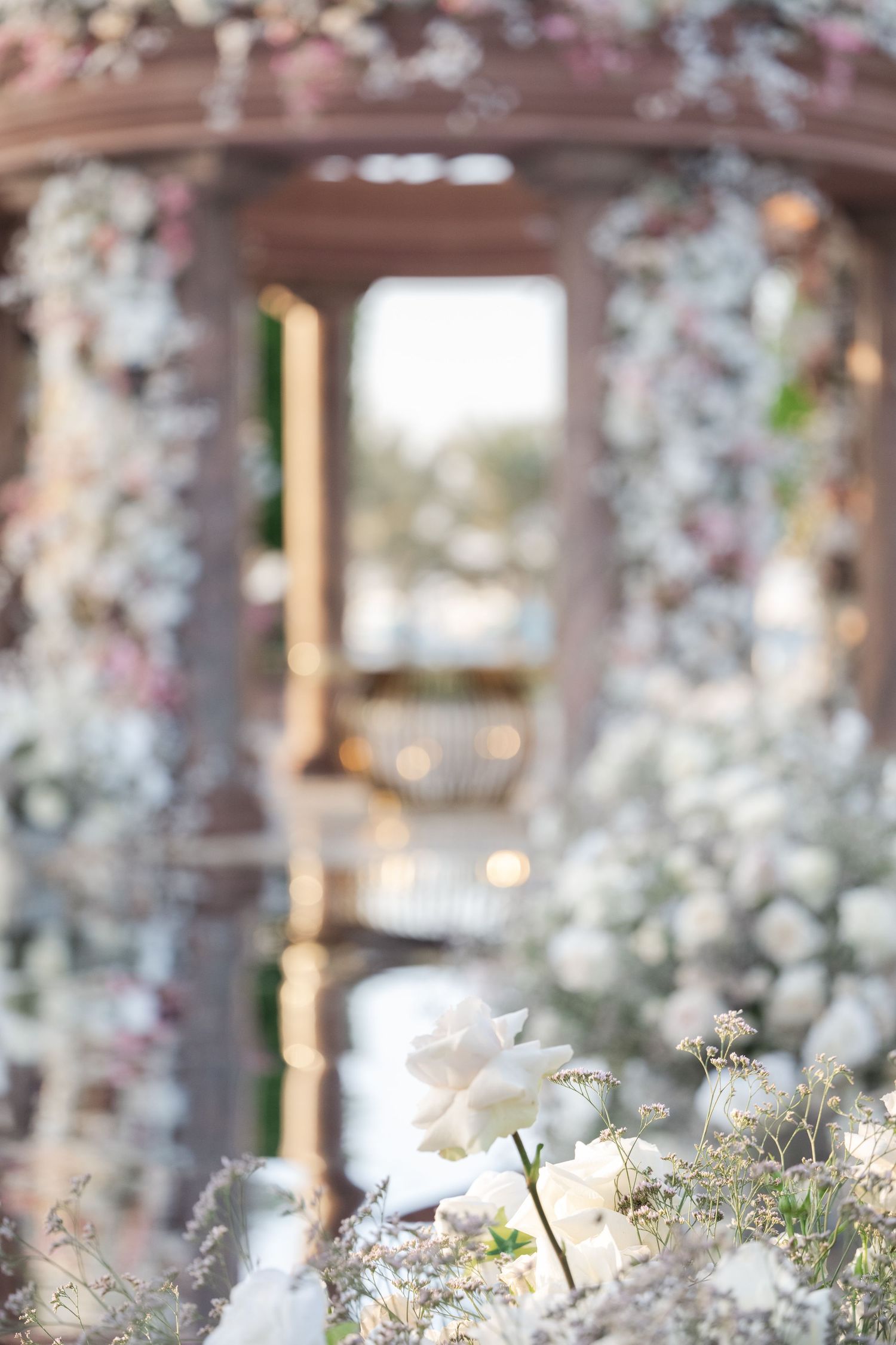 Dreamy close-up of a floral-adorned wedding arch with blurred background.