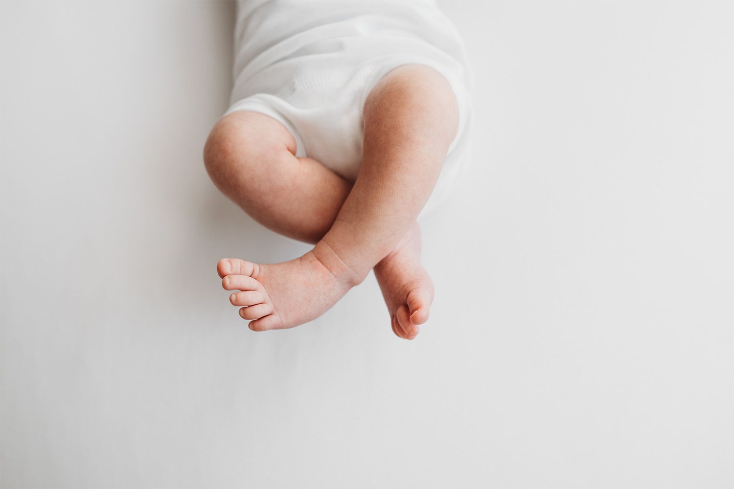 Close-up view of tiny baby feet against a soft white background in a minimalist style.
