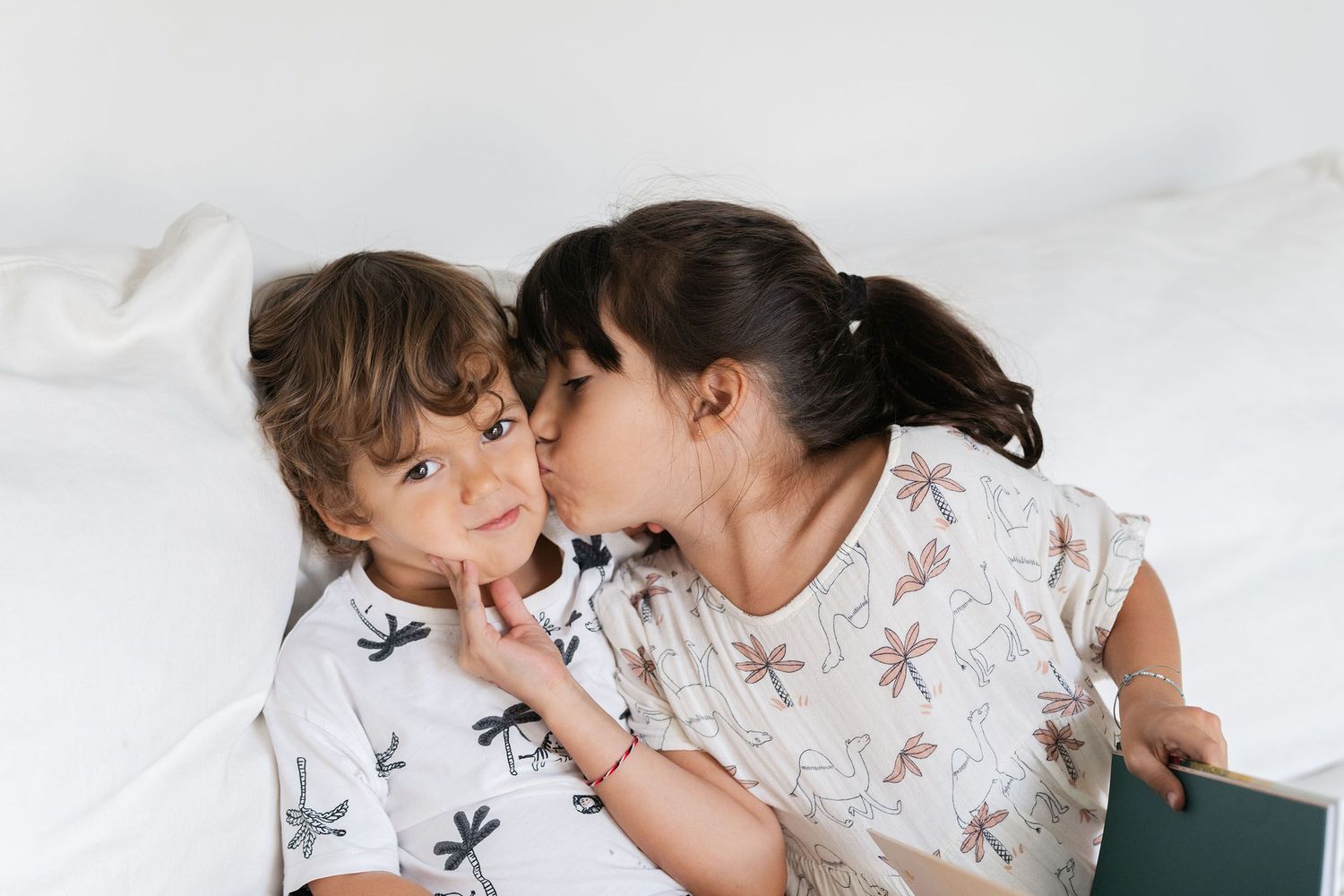 Two young children in matching pajamas sharing a sweet moment together.