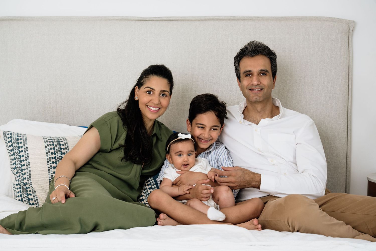 Family relaxing together on bed in casual home setting.
