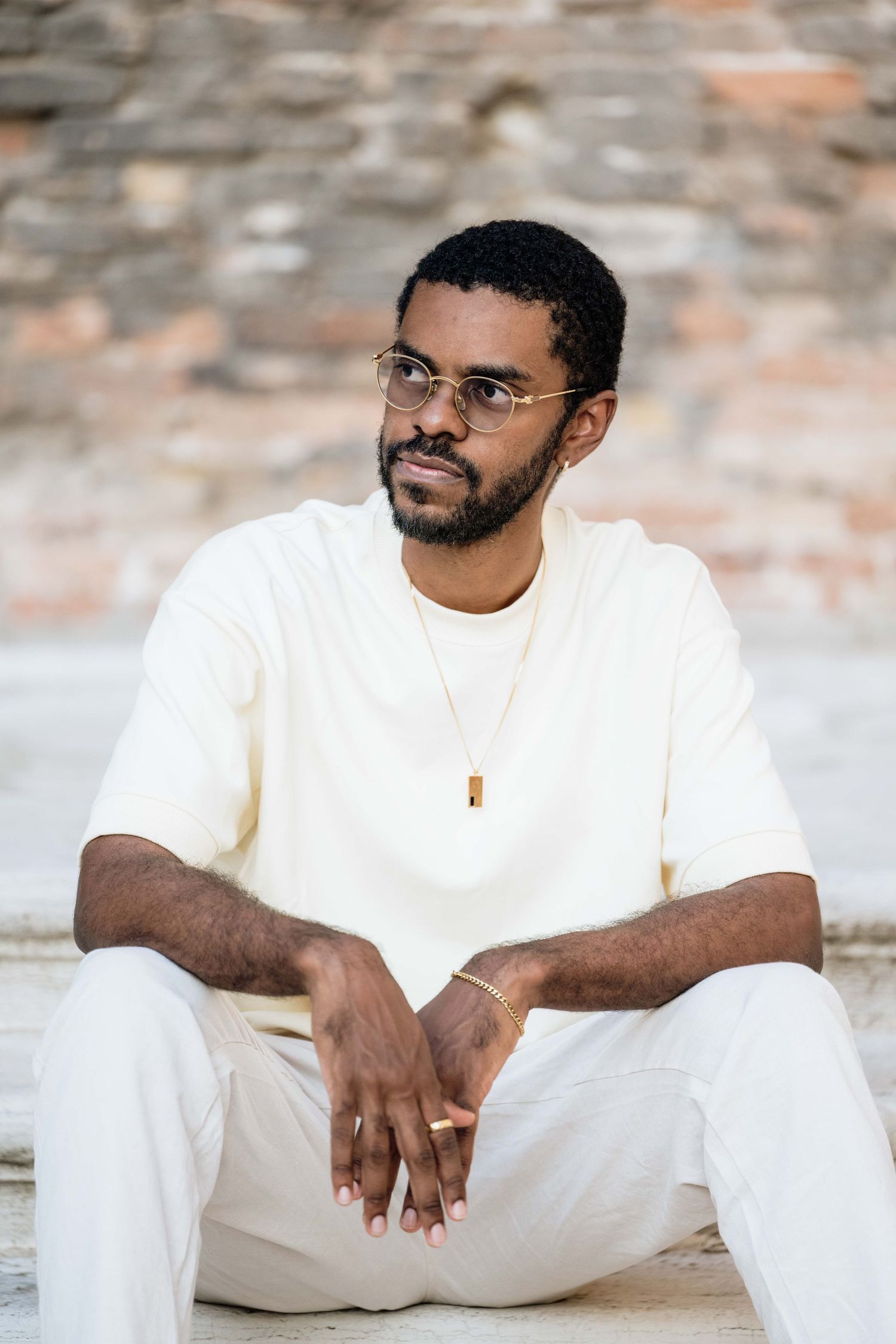 Casual portrait series of person in white clothing sitting on stone steps.