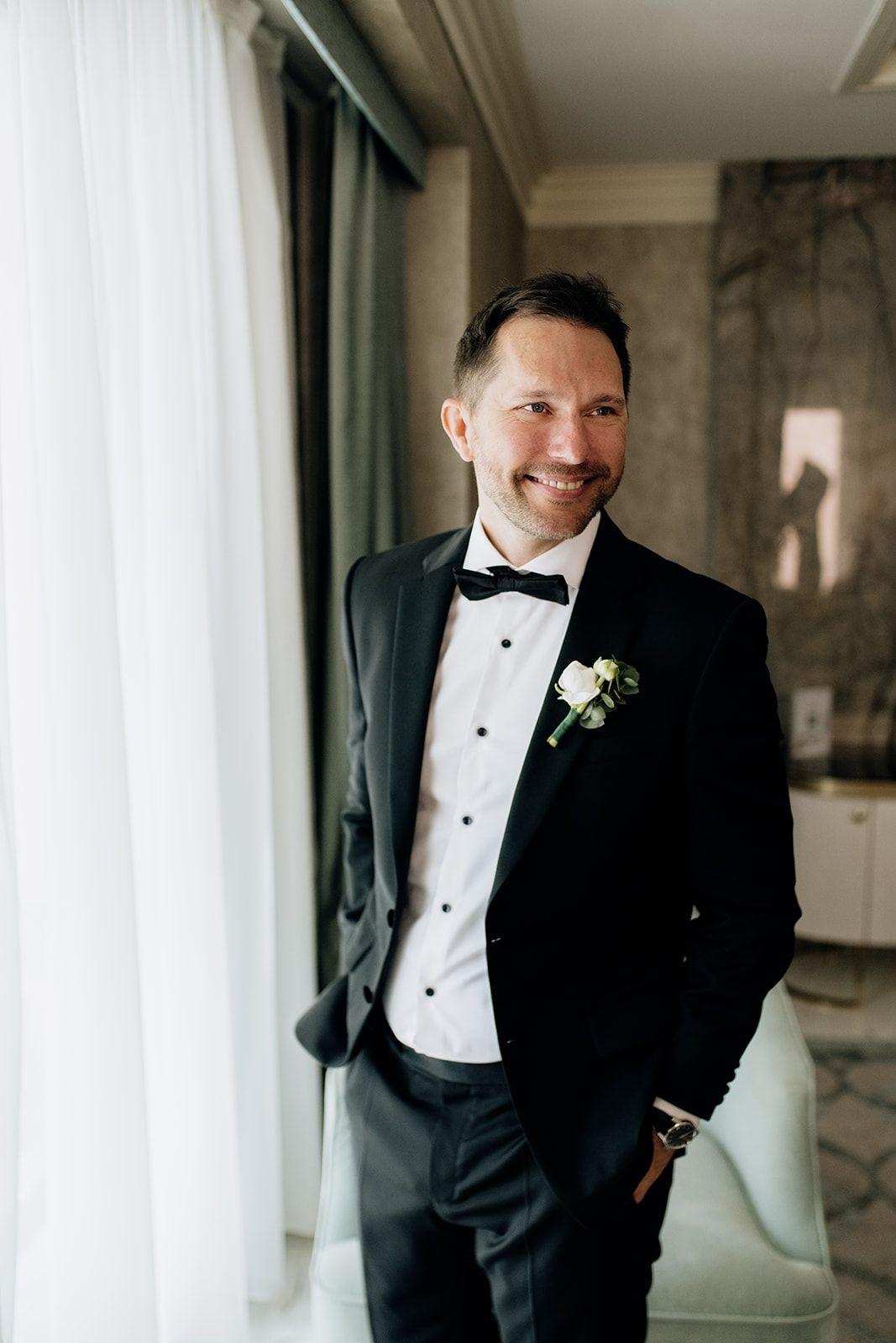 Groom in classic tuxedo smiles during wedding day portraits.