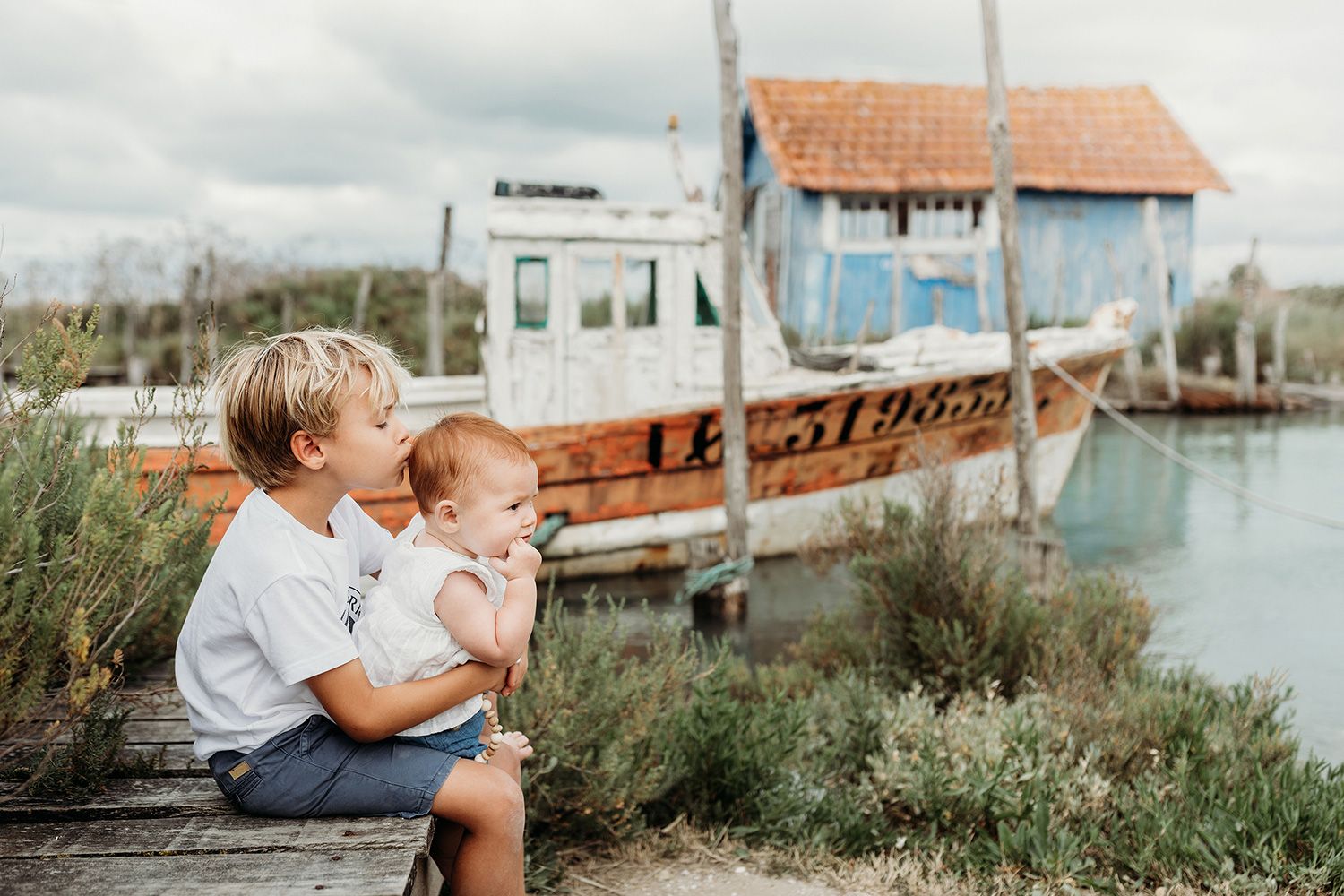 Children play together near a coastal marina with boats and docks visible in the background.
