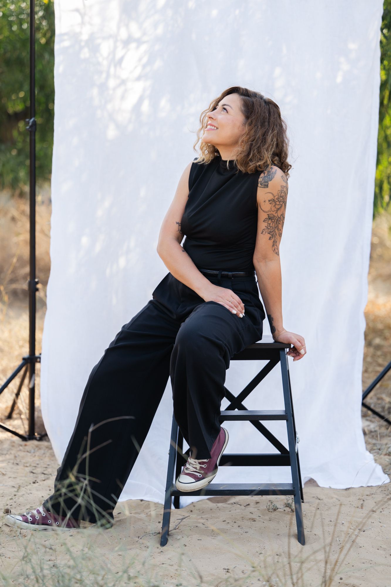 A figure in a black dress poses against a white backdrop in a series of artistic outdoor portraits.