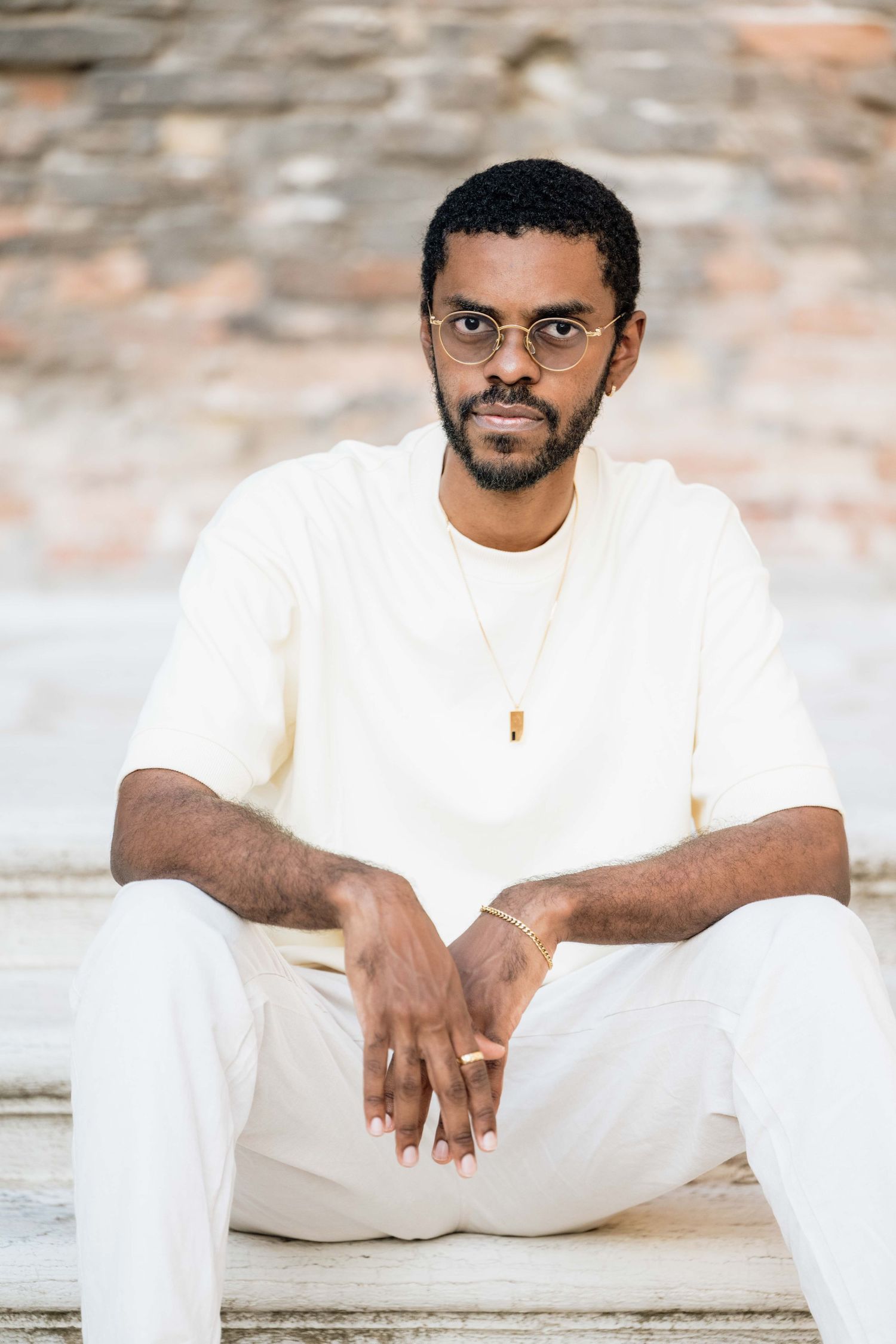 Person in white clothing sitting on a textured surface in casual poses.
