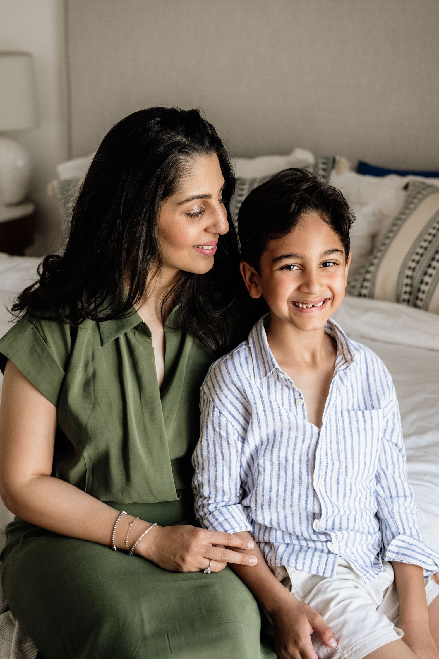 Intimate family portrait on bed showing genuine smiles and connection.