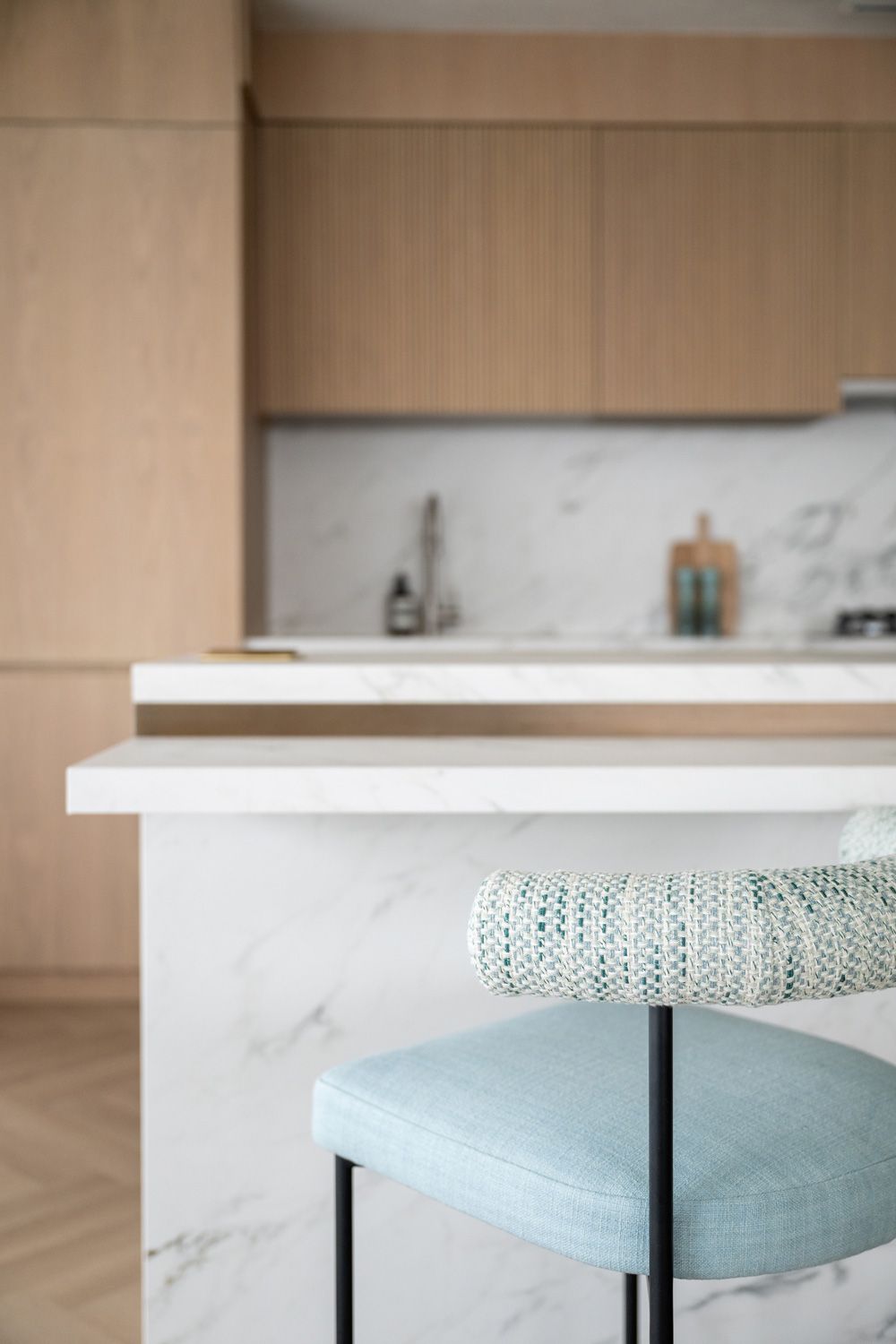Modern kitchen design features sleek wooden cabinets and white marble countertops with minimalist hardware details.