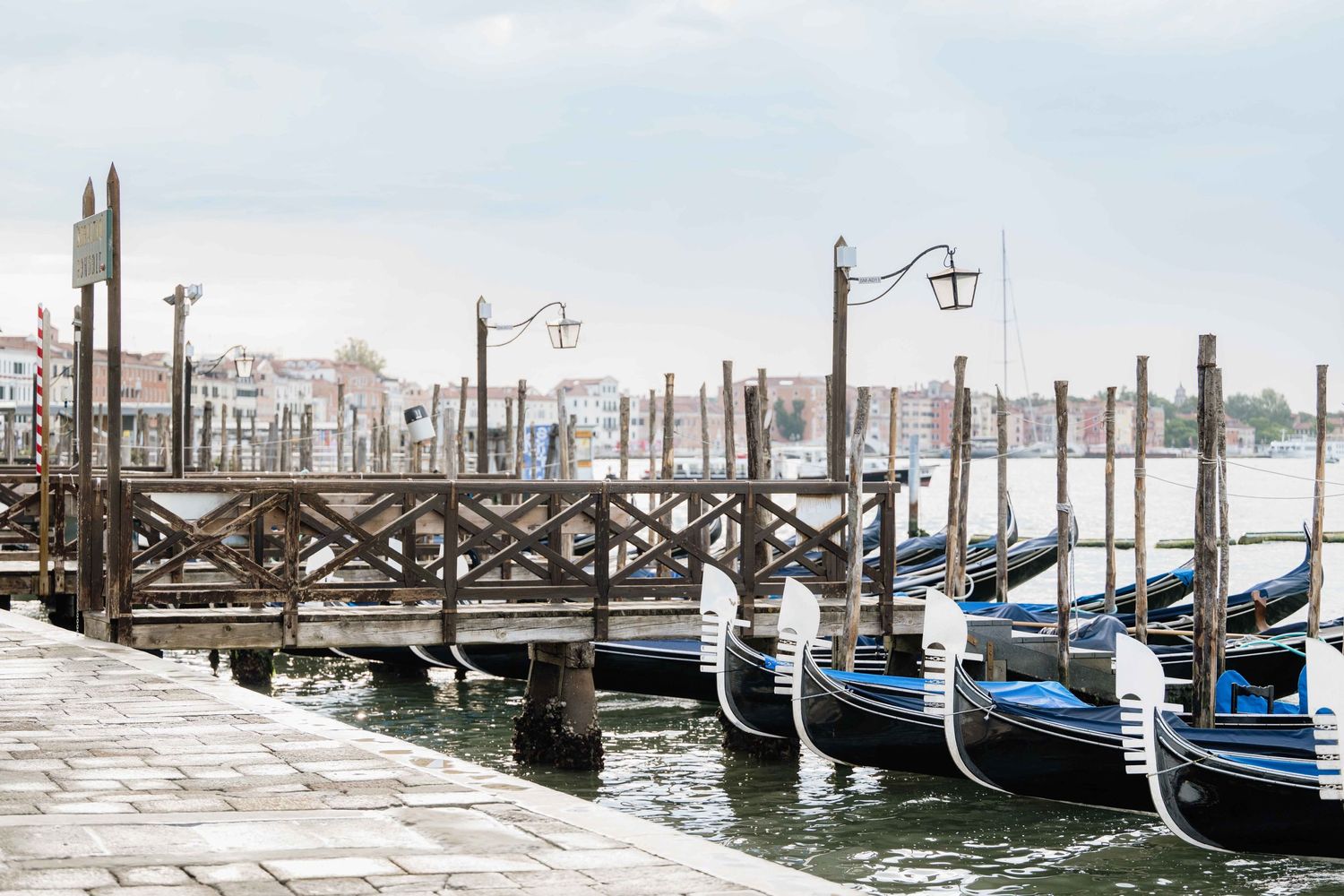 Panoramic view of empty gondola moorings along Venice's waterfront on a misty day.