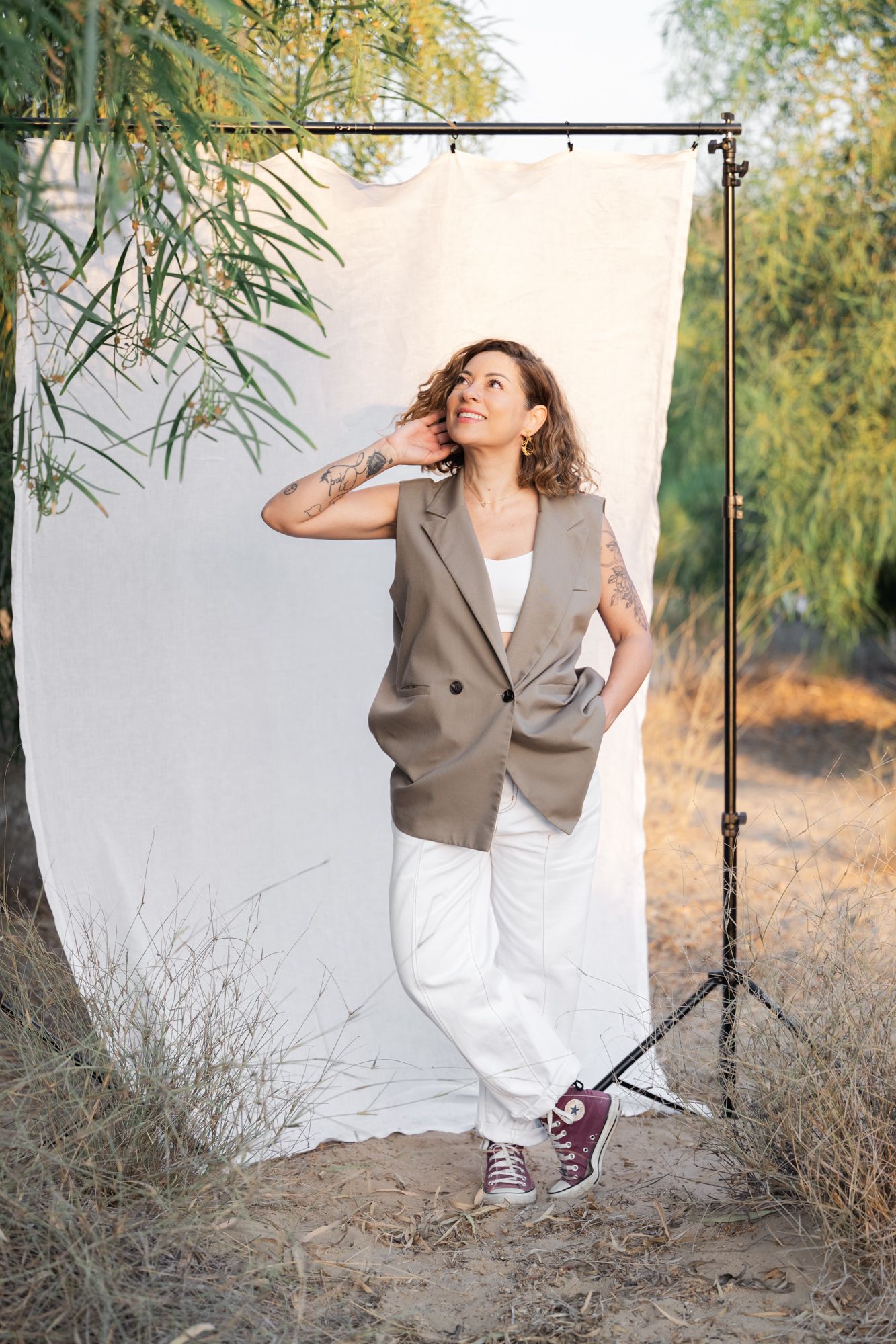 A series of four artistic outdoor portraits featuring a lady in a brown blazer and white pants against a natural backdrop.