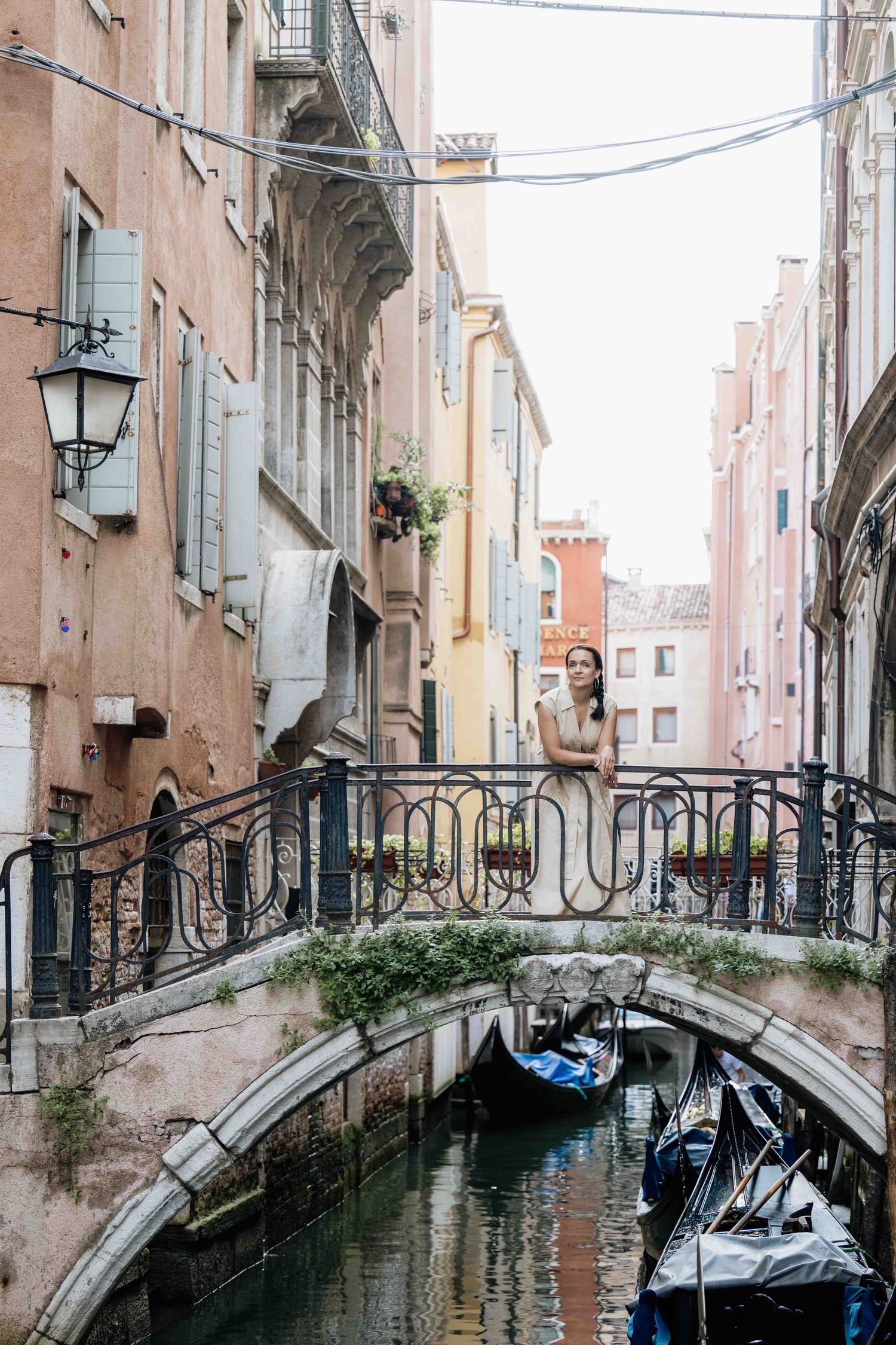 Stone bridge spans a quiet Venetian canal between weathered historic buildings.