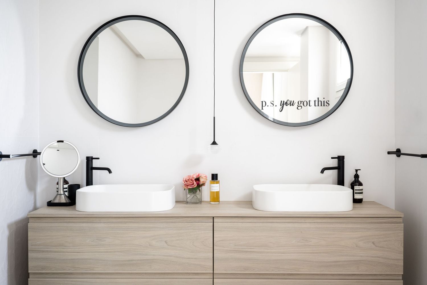 Modern bathroom interior with multiple round mirrors and wooden vanity against white walls.