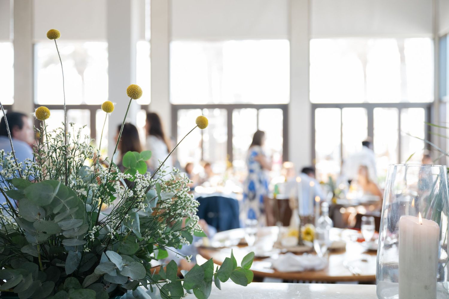 Yellow billy balls and delicate white flowers in a sunny reception venue.