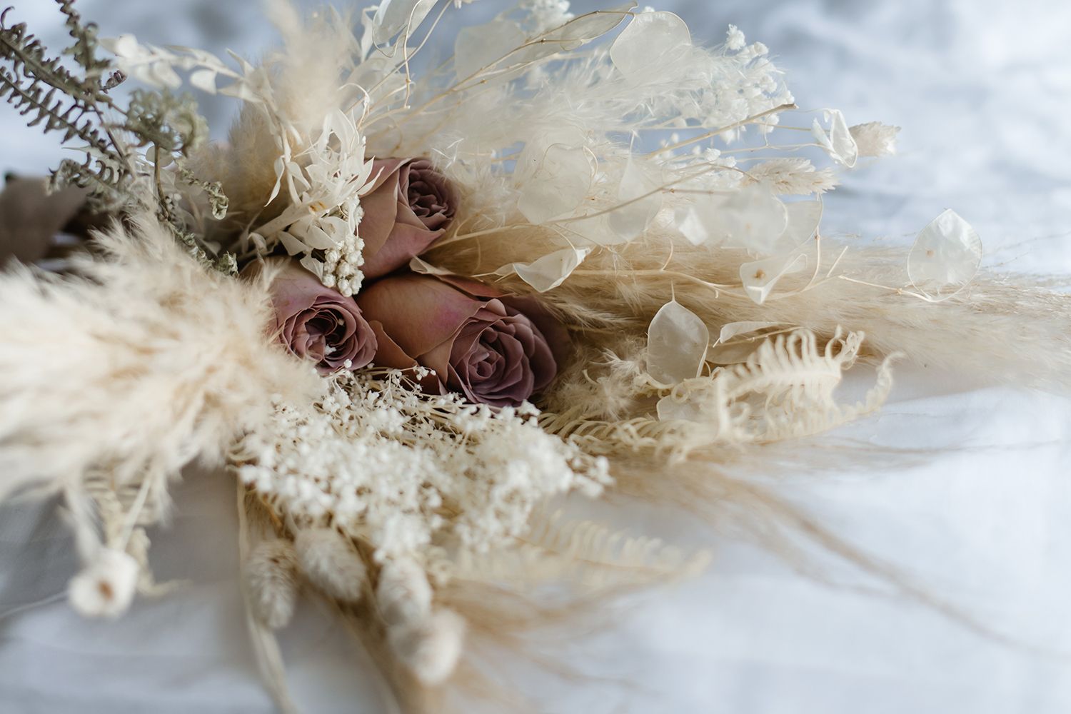 Romantic arrangement of dried flowers with muted roses and pampas grass.