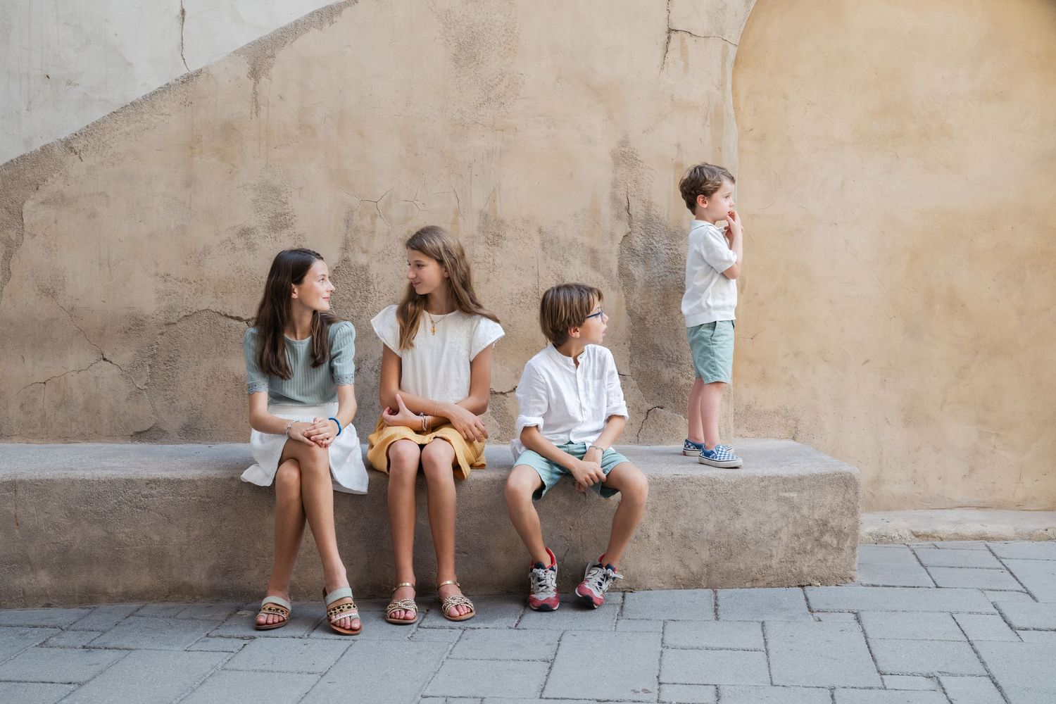 Group sitting casually against stone wall outdoors.