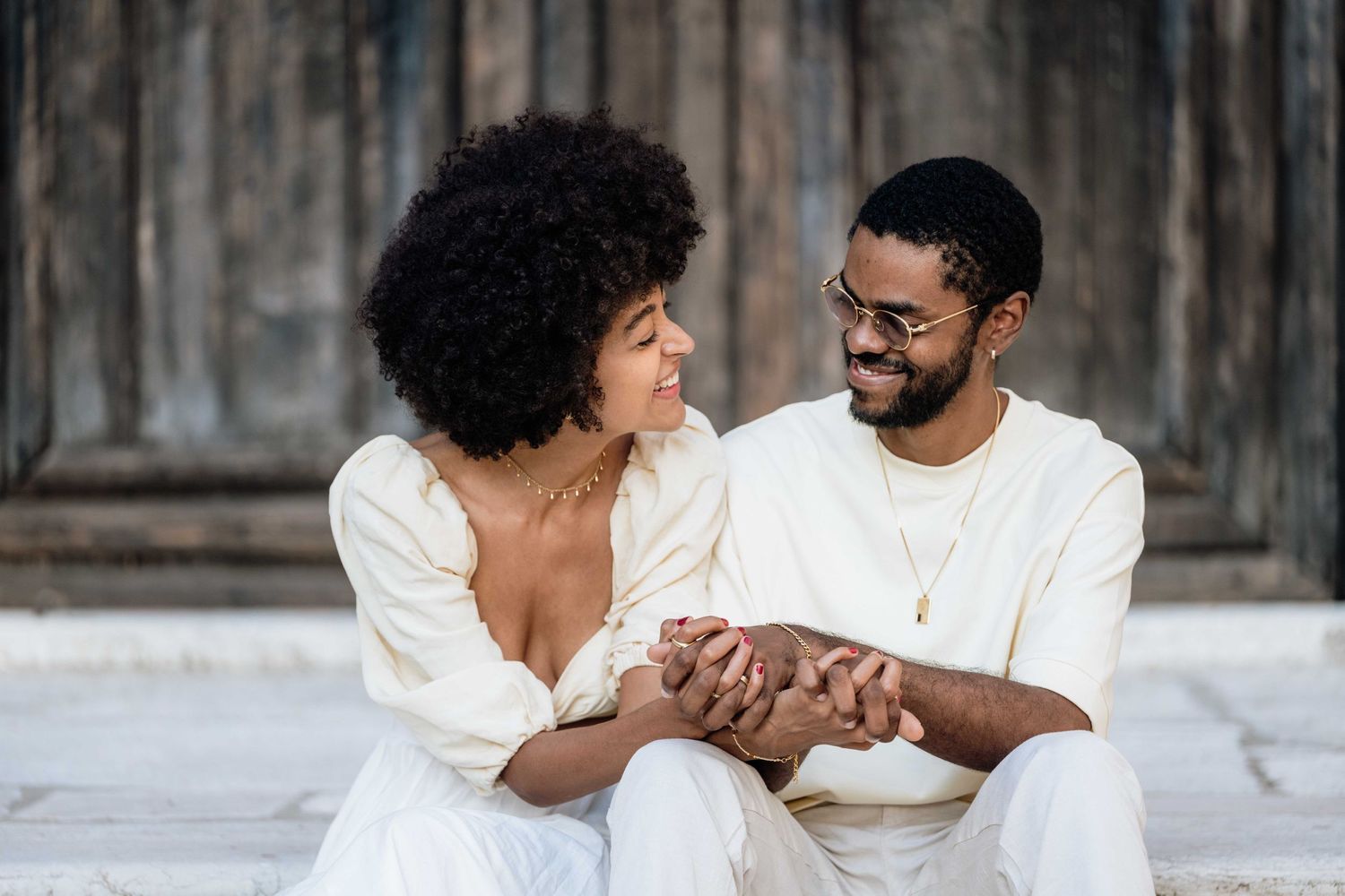 A joyful couple shares laughter while sitting together on stone steps.