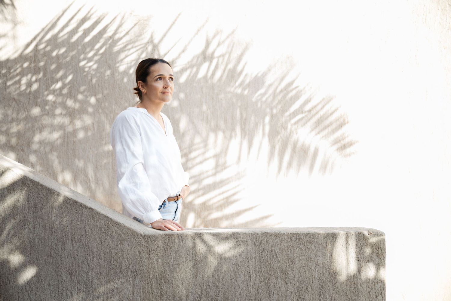 Artistic portraits with palm frond shadow patterns on white wall.