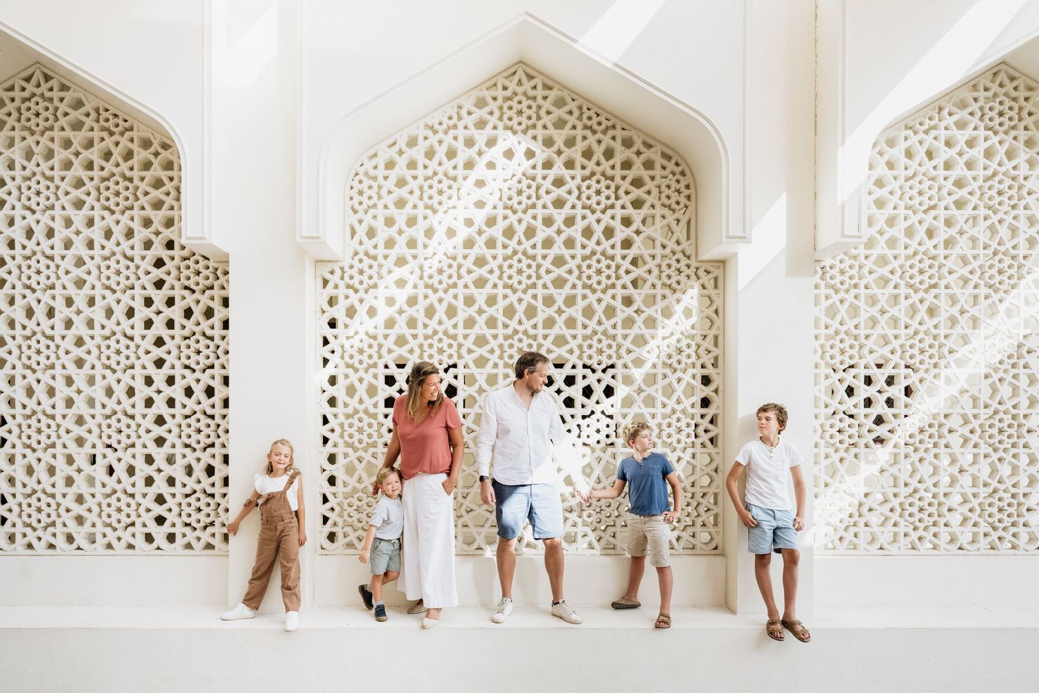 Group photo sequence against decorative white lattice wall in casual attire.