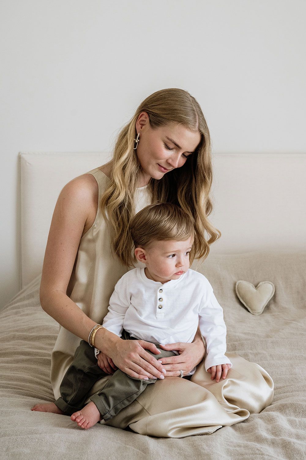 A tender moment captured in a series of minimalist photographs showing mother and child bonding on a light colored bed.