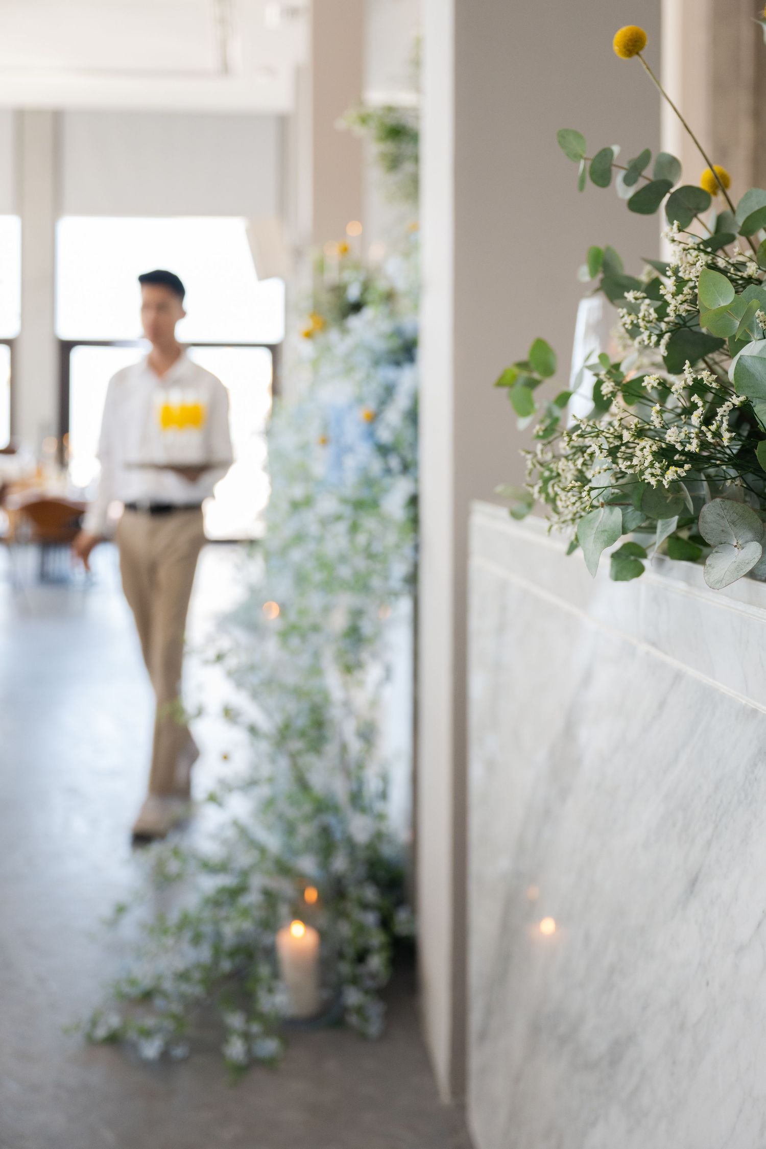 Candlelit hallway decorated with cascading greenery and white floral arrangements.