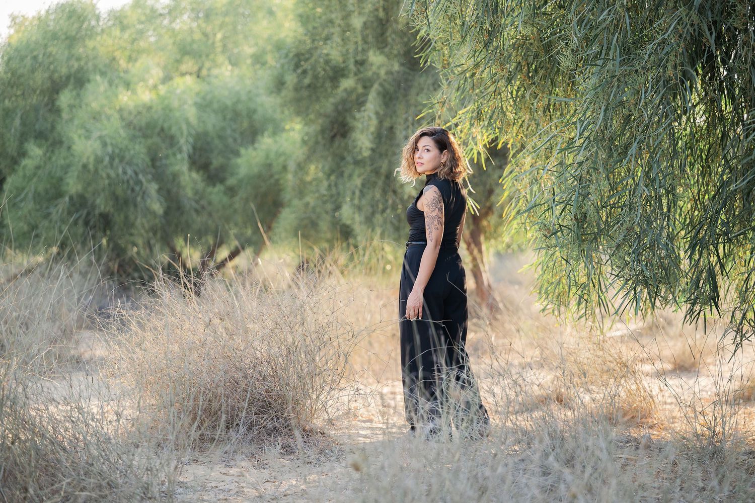 Natural outdoor portrait session among willow trees in golden evening light.