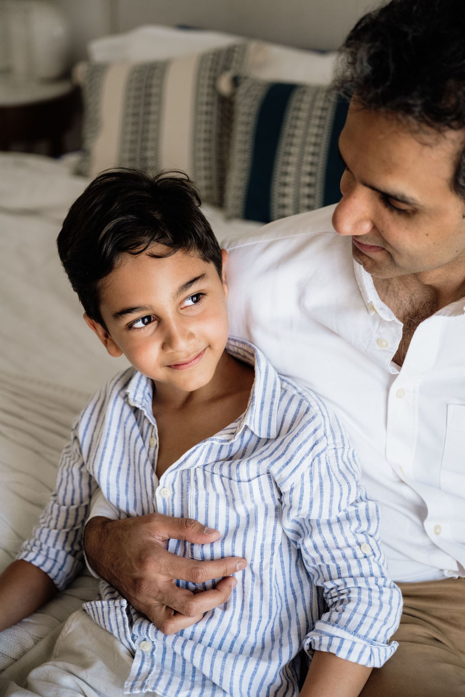 Playful family moment captured on bed with blue and white decor.