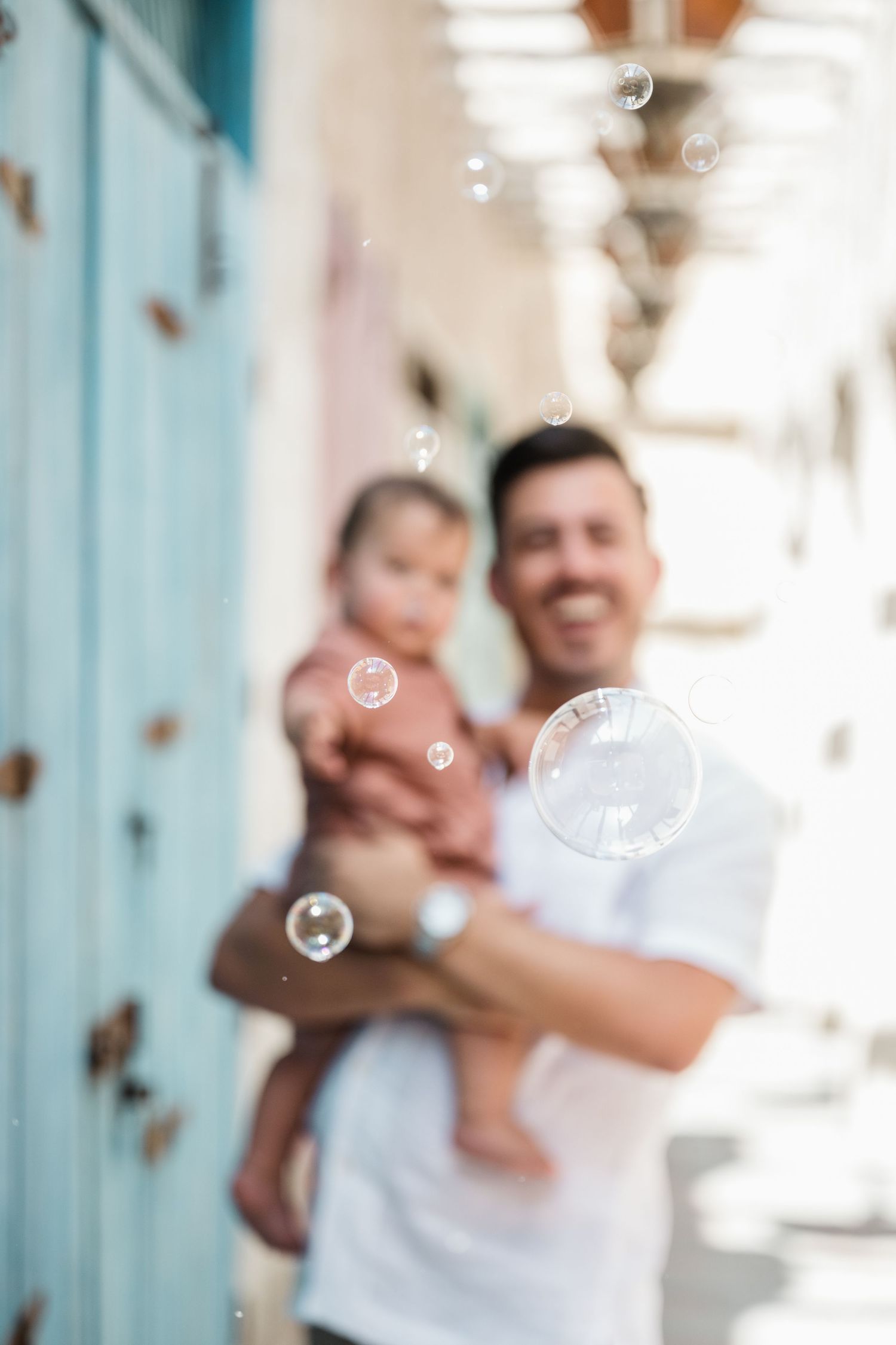 Playful family moment with soap bubbles against blue doors.